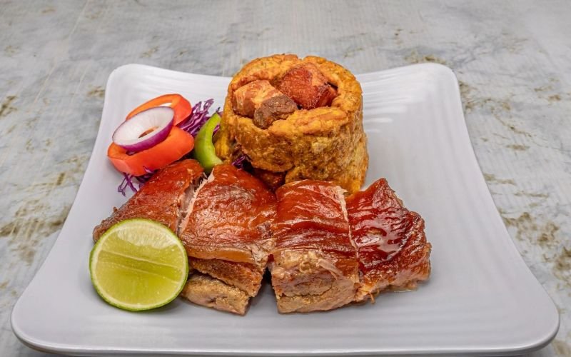 Experience the heart of Dominican cuisine with our handcrafted Mofongo and mouthwatering Pernil, served with a choice of irresistible sauces—your next favorite meal is just an online order away!
